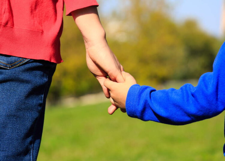 Mother holding hand of her son outdoors